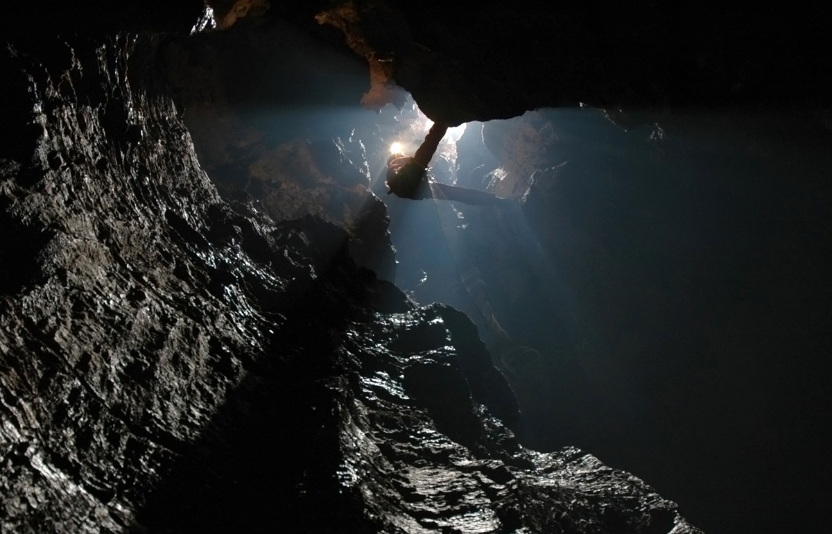 Caver using SRT to descend deep underground in a hidden cave system