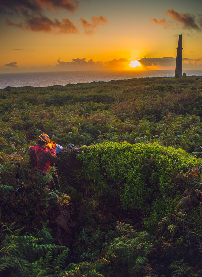 Mine explorer in Cornwall emerging from a mine shaft at sunset after a long SRT trip. 