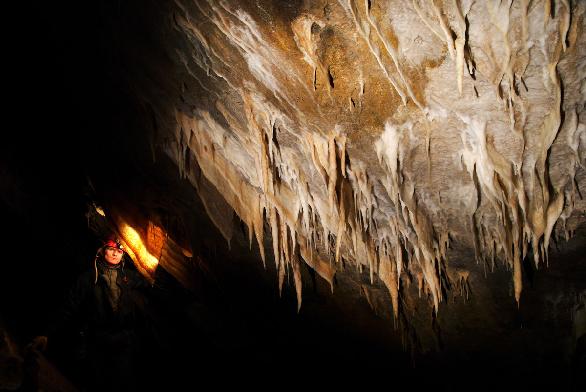 Caver equipped to explore and discover some amazing Stalactites deep underground