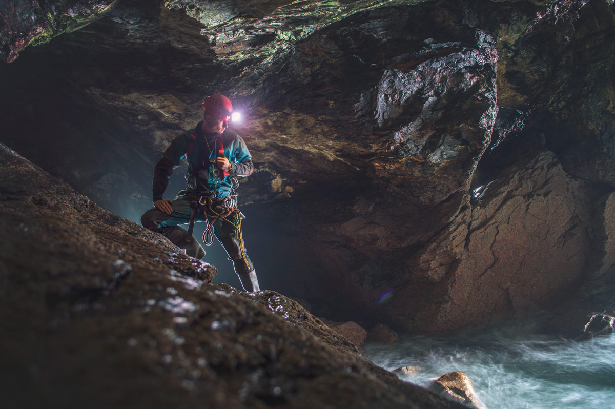 Mine Explorer in a dramatic position in a Cornish sea cave wearing a Camp Rockstar Helmet