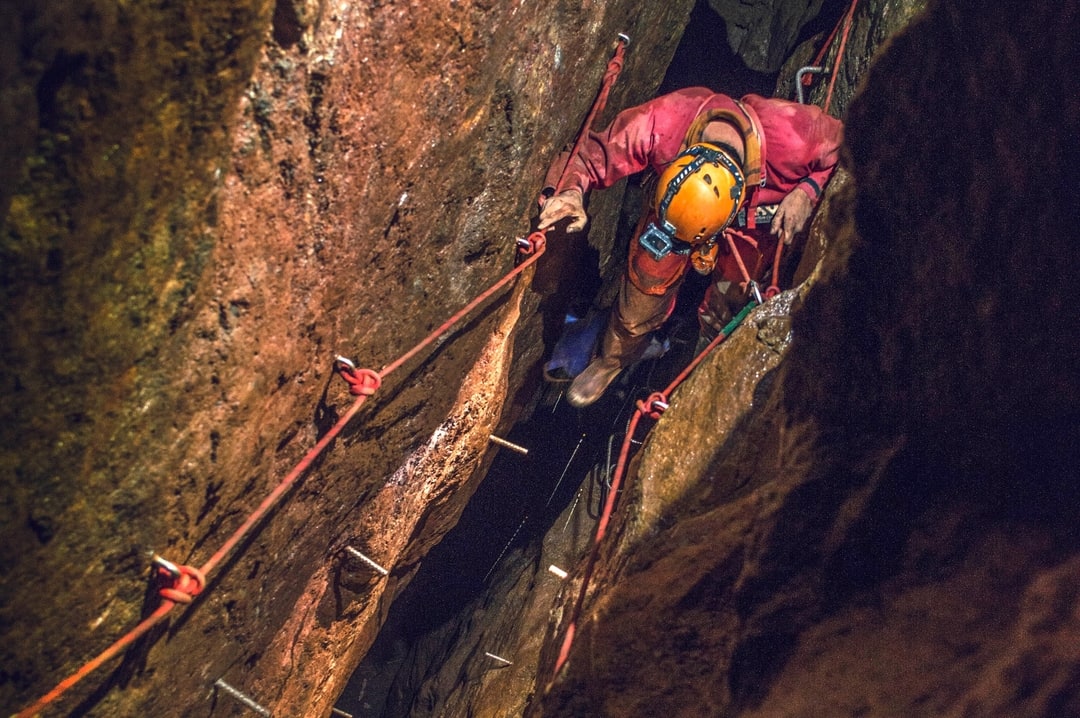 Exploring a tine mine in St. Just, West Cornwall. Mine explorer climbing up through a chasm 