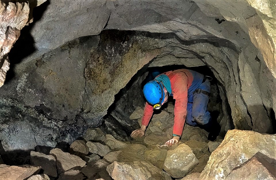 Mine explorer crawling through a tunnel in a Cornish tin mine