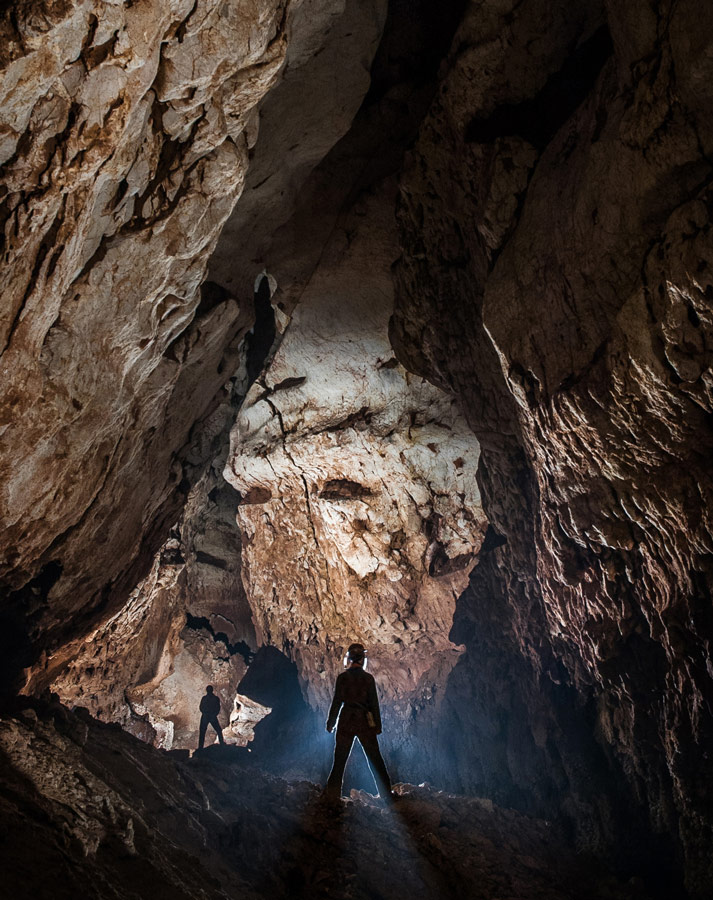 Caver in a beautiful cave chamber admiring formations in the limestone