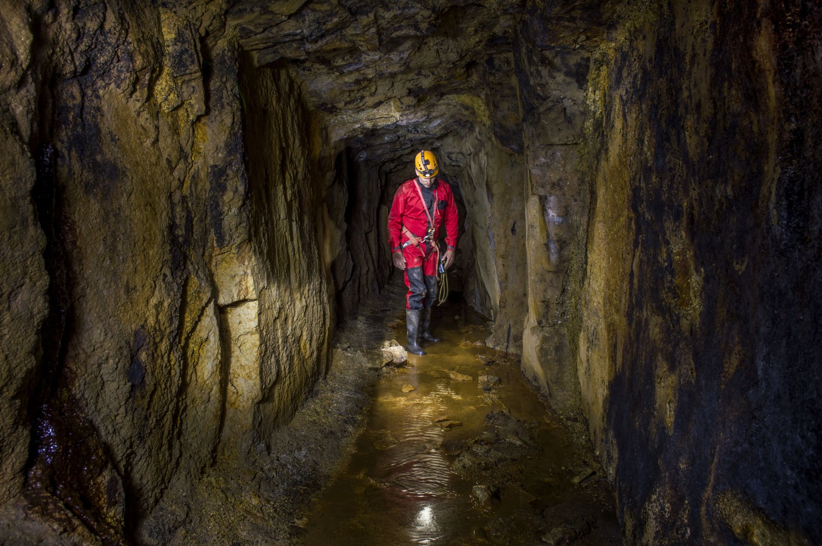 Mine explorer walking along a cross cut in a Cornish tin mine.