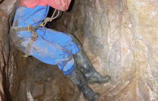 A mine explorer carefully negotiates a deep chasm in a Cornish tin mine with Cornwall Underground Adventures.
