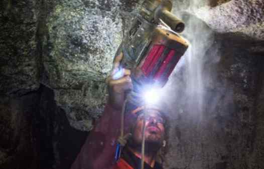 Cornwall Underground Adventure guide bolting an abseil anchor in a Cornish tin mine